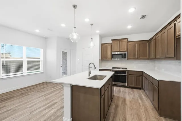 a view of a kitchen with stainless steel appliances granite countertop a stove top oven a sink and a refrigerator