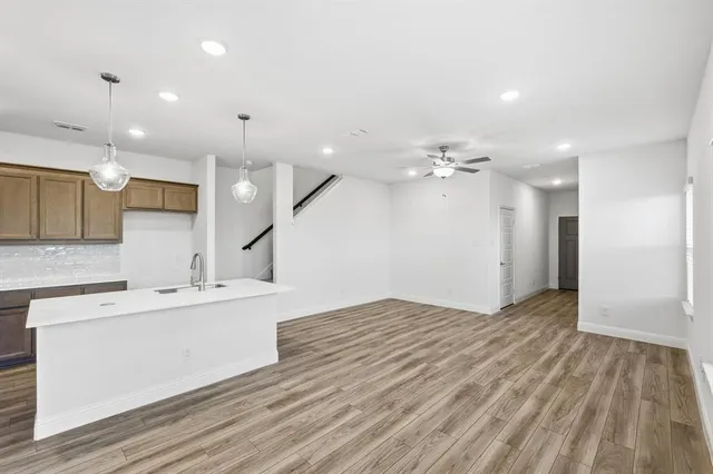 a large kitchen with a large counter top a sink stainless steel appliances and cabinets