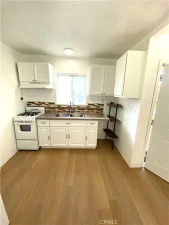 a view of kitchen with a sink a stove and cabinets