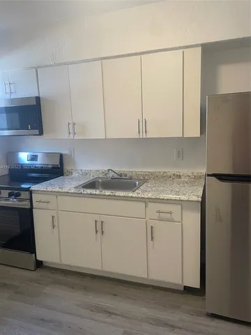 a kitchen with granite countertop white cabinets and white appliances