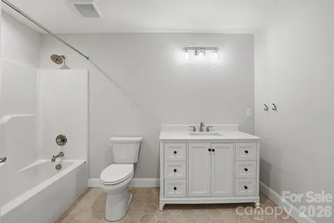 a bathroom with a granite countertop toilet a sink a mirror and bathtub