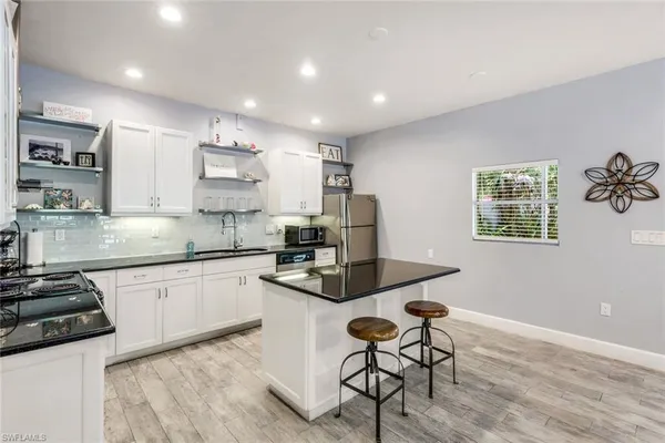 a kitchen with stainless steel appliances granite countertop a stove top oven a sink a dining table and chairs with wooden floor