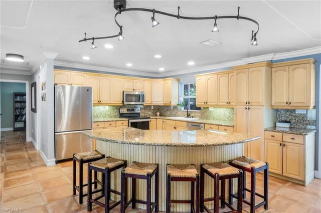 a kitchen with stainless steel appliances granite countertop a table chairs sink and cabinets