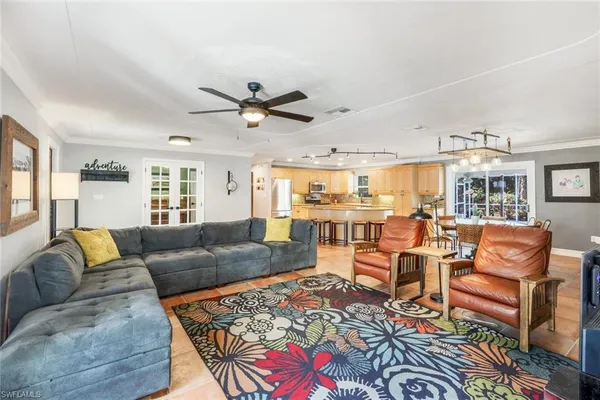 a living room with furniture kitchen view and a large window