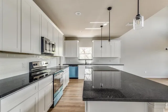 a kitchen with stainless steel appliances granite countertop a sink a stove and a refrigerator