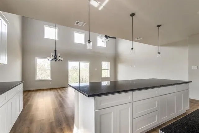 a kitchen with stainless steel appliances granite countertop a sink a window and wooden floor