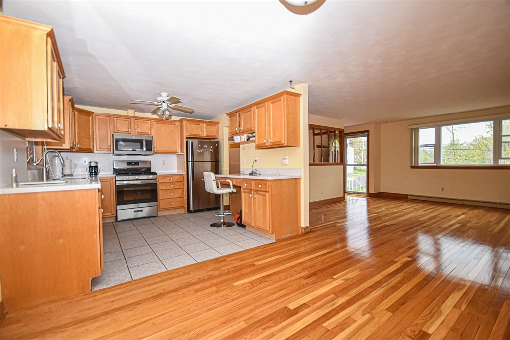 5 Brewster Road Randolph, MA 02368 - Photo 11 of 21 a kitchen with stainless steel appliances granite countertop a stove top oven a sink dishwasher and a refrigerator with wooden floor