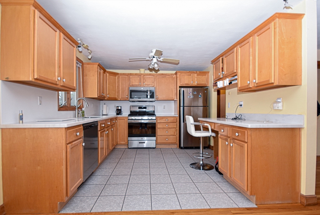 5 Brewster Road Randolph, MA 02368 - Photo 8 of 21 a kitchen with stainless steel appliances granite countertop a refrigerator a sink dishwasher a stove with wooden cabinets