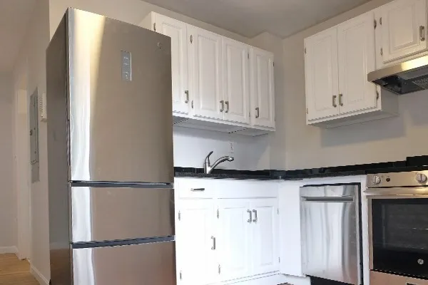 a kitchen with granite countertop white cabinets and refrigerator