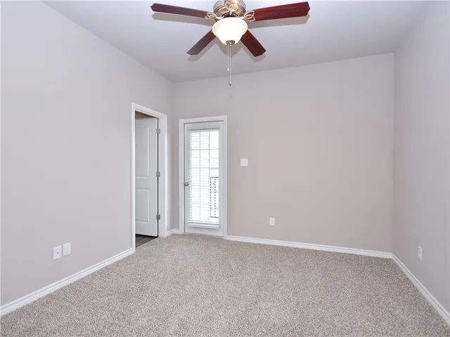 a view of an empty room and chandelier fan