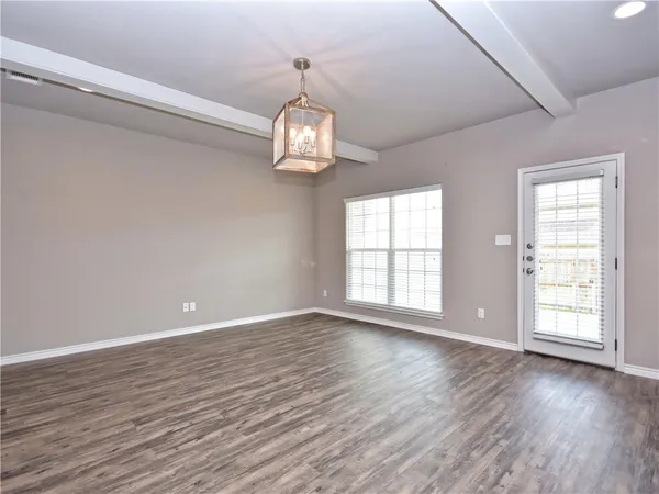 a view of empty room with wooden floor and window