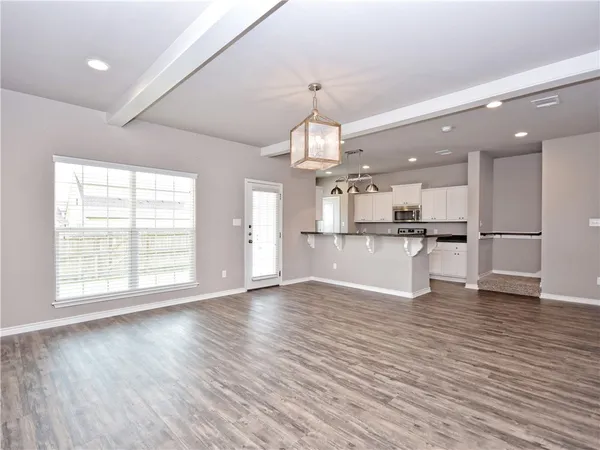 a view of a kitchen with a refrigerator a kitchen island wooden floor and a window