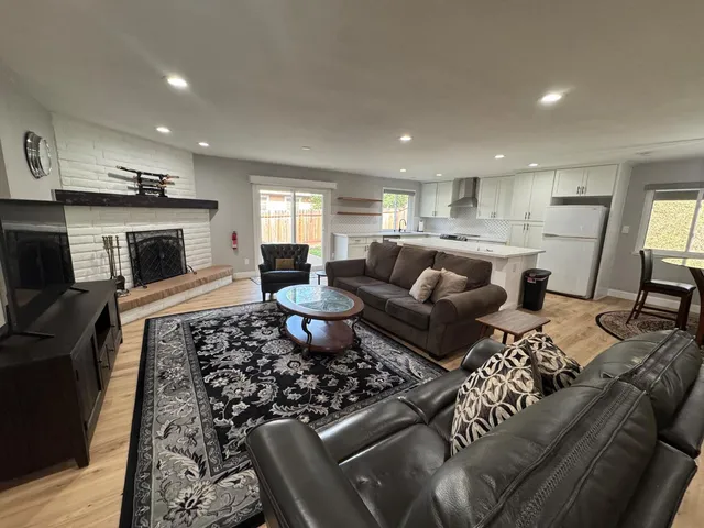 a living room with furniture a fireplace and a open kitchen view