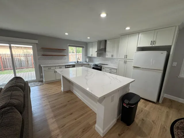 a kitchen with a refrigerator a sink dishwasher a stove and a refrigerator with wooden floor