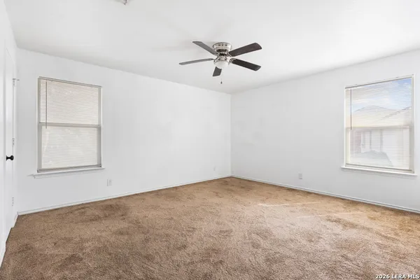 an empty room with a window and a fan