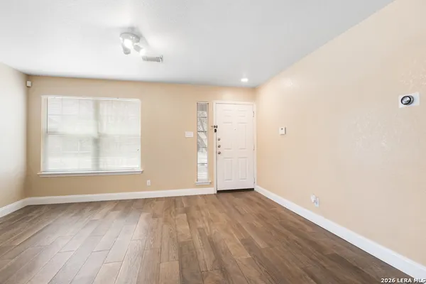 an empty room with wooden floor and windows