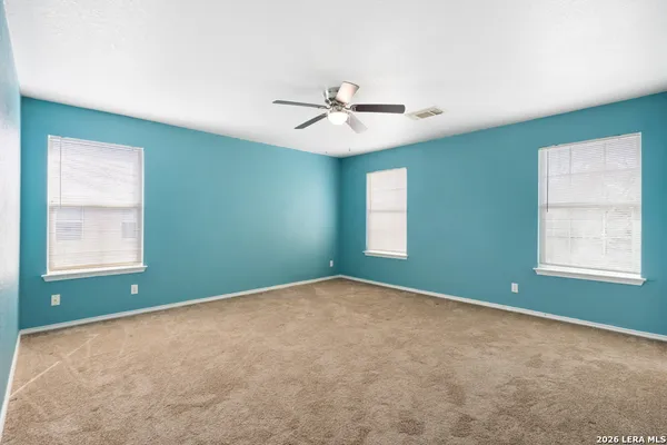 an empty room with windows and fan