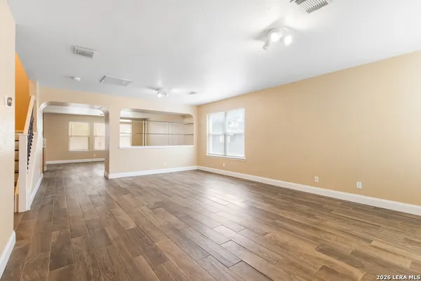 an empty room with wooden floor and windows