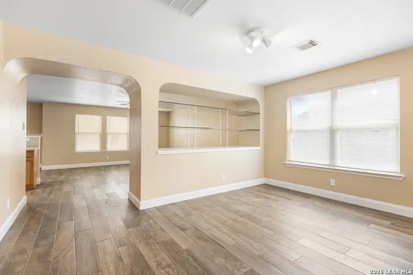 a view of an empty room with wooden floor and a window