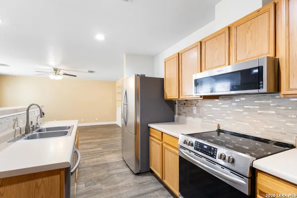 a kitchen with granite countertop a stove top oven a sink dishwasher and a refrigerator with wooden floor