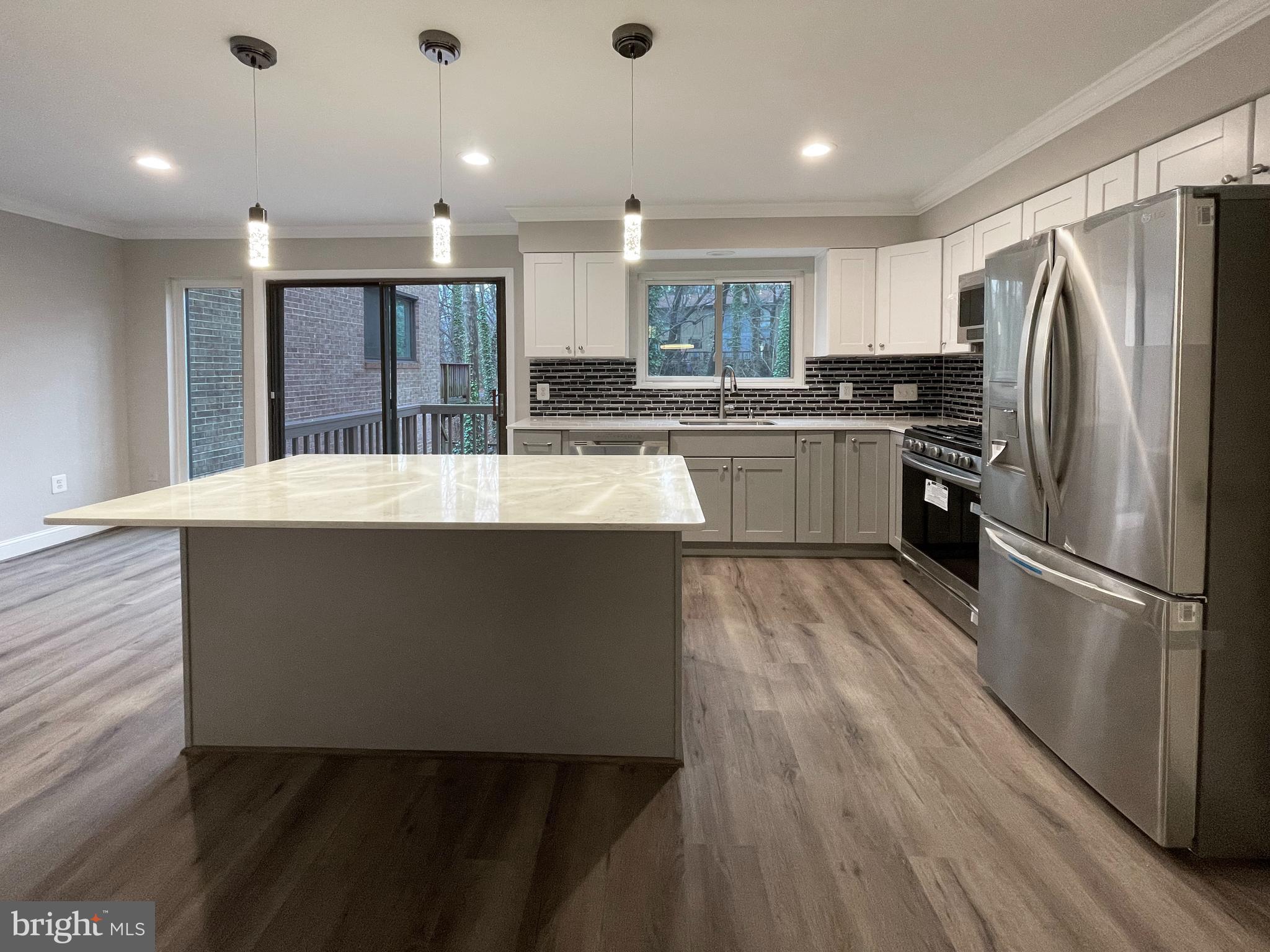 11968 Greywing Court Reston, VA 20191 - Photo 1 of 13 a large kitchen with kitchen island a stove a sink dishwasher a refrigerator and white cabinets with wooden floor