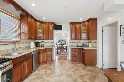 a kitchen with stainless steel appliances granite countertop wooden cabinets a stove a sink a dining table and chairs