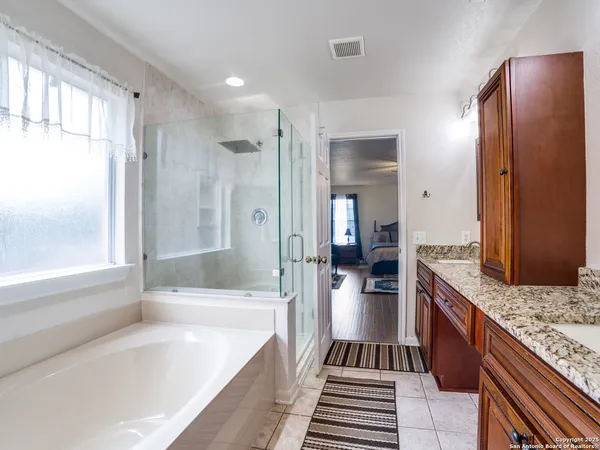a bathroom with a granite countertop tub sink a mirror and a shower