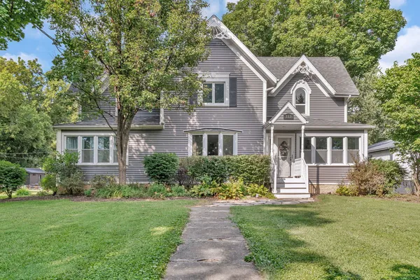 a front view of a house with a garden and trees