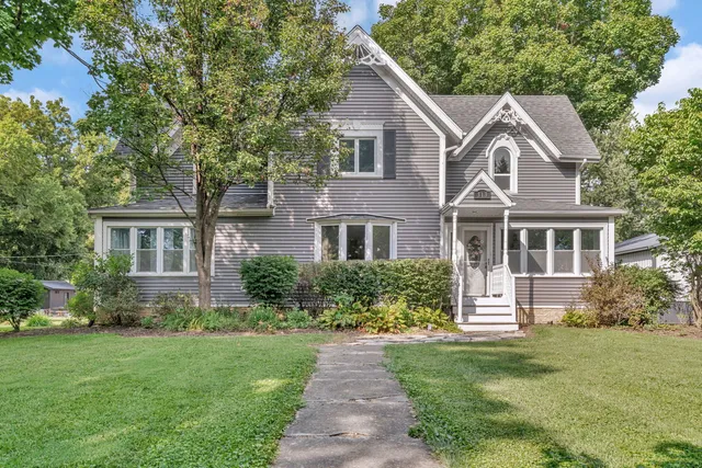a front view of a house with a garden and trees