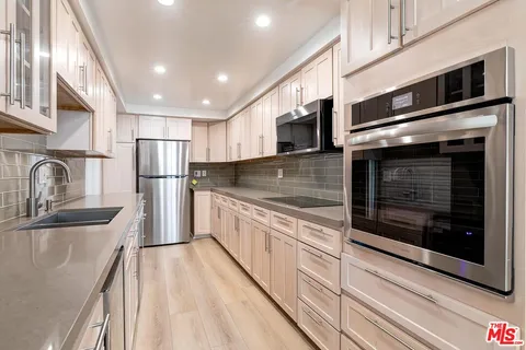 a kitchen with stainless steel appliances kitchen island granite countertop a refrigerator stove and sink