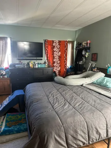a bedroom with a bed window table and television