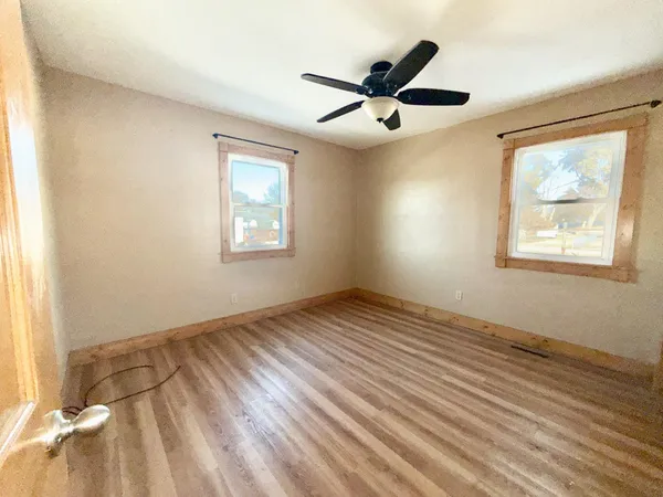 a view of empty room with wooden floor and fan