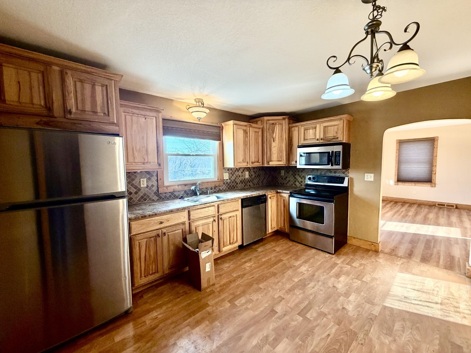 716 Viaduct Road Savanna, IL 61074 - Photo 3 of 19 a kitchen with granite countertop a refrigerator a sink dishwasher a stove top oven a dining table and chairs with wooden floor