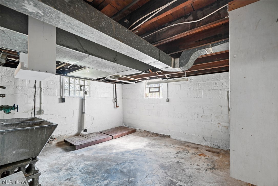503 Ravenna Road Newton Falls, OH 44444 - Photo 20 of 34 Unfinished basement featuring exposed ceiling joists and ductwork, painted cinder block walls, concrete flooring, and a utility sink