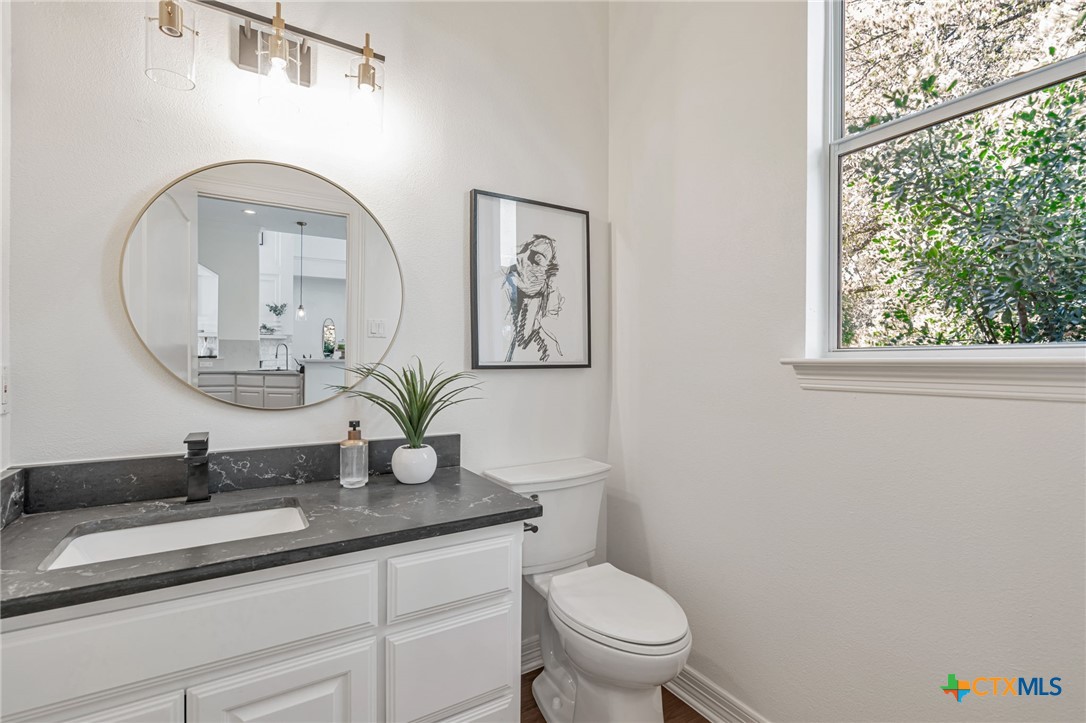 200 Tovas Secret Cove Georgetown, TX 78628 - Photo 24 of 31 a bathroom with a granite countertop toilet a sink and a mirror