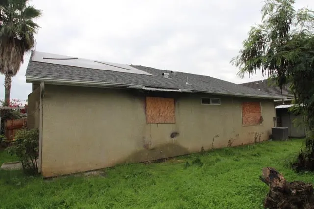 a backyard of a house with potted plants and wooden fence
