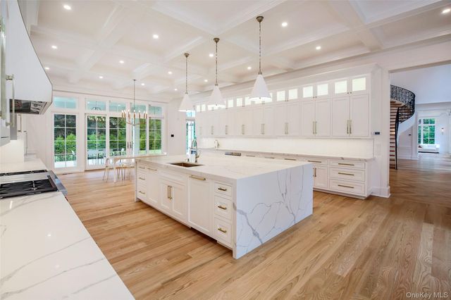 a large white kitchen with a large window a sink and a stove