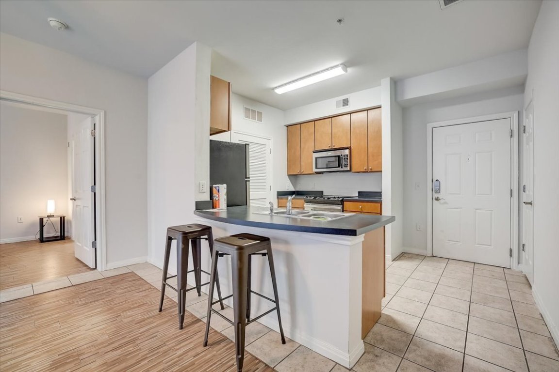 2515 Pearl Street, Unit 212 Austin, TX 78705 - Photo 2 of 10 a kitchen with stainless steel appliances a sink a stove a refrigerator cabinets and dining table