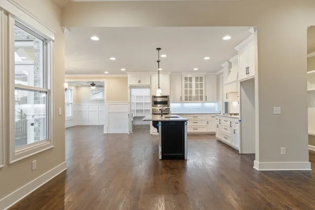 a kitchen with granite countertop a sink stove a refrigerator and white cabinets with wooden floor