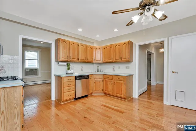 a open kitchen with granite countertop a stove top oven a sink dishwasher and white cabinets with wooden floor