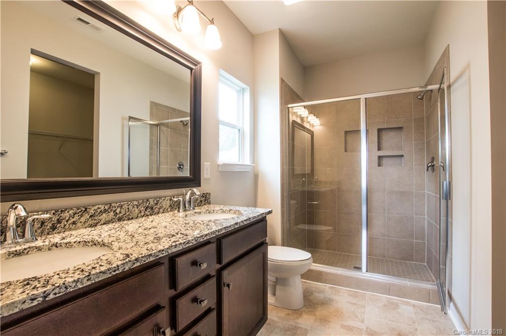 1889 Larkspur Way Tega Cay, SC 29708 - Photo 25 of 29 a bathroom with a granite countertop sink toilet mirror and shower