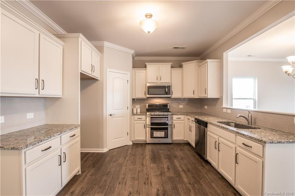 1889 Larkspur Way Tega Cay, SC 29708 - Photo 9 of 29 a kitchen with granite countertop white cabinets and white appliances