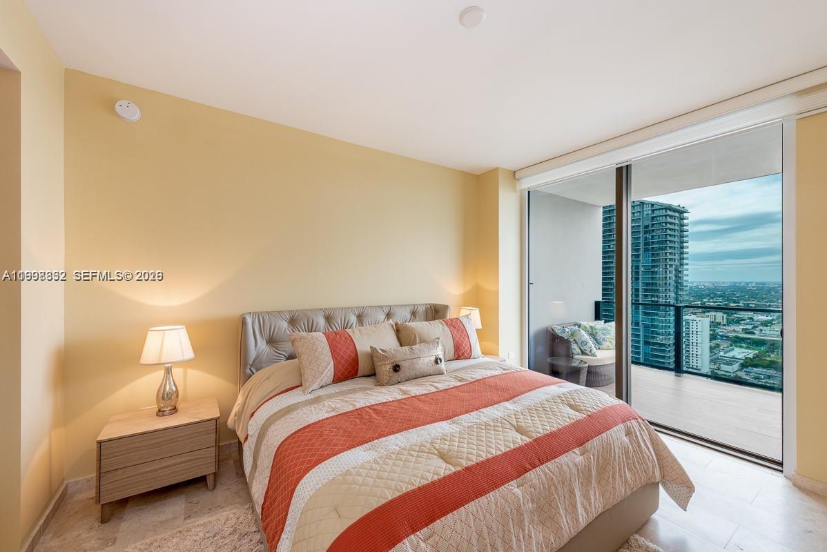 68 Southeast 6th Street, Unit 3006 Miami, FL 33131 - Photo 3 of 10 a bedroom with a bed and a large window