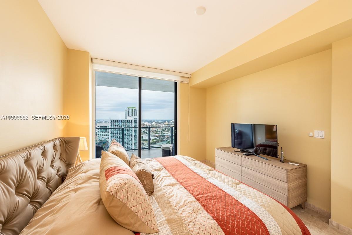 68 Southeast 6th Street, Unit 3006 Miami, FL 33131 - Photo 4 of 10 a bed sitting in a bedroom next to a window