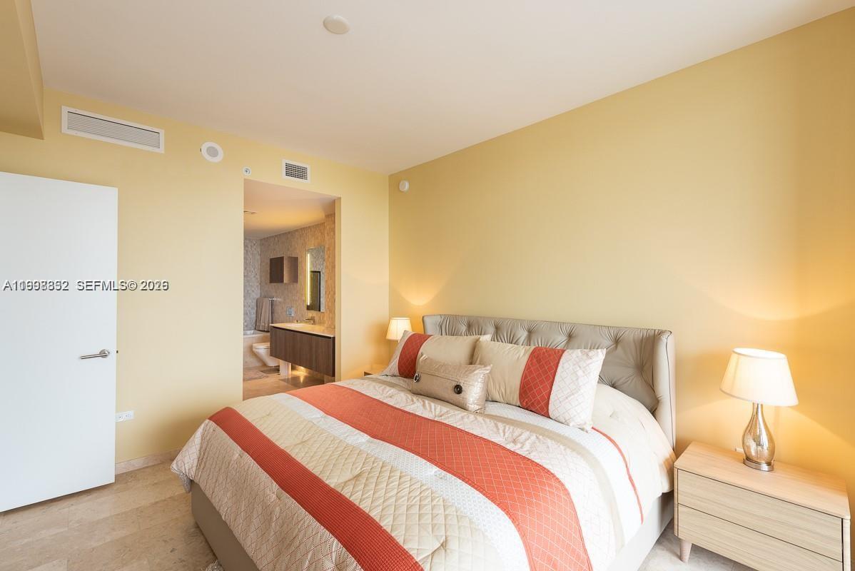 68 Southeast 6th Street, Unit 3006 Miami, FL 33131 - Photo 5 of 10 a bedroom with a bed and a lamp
