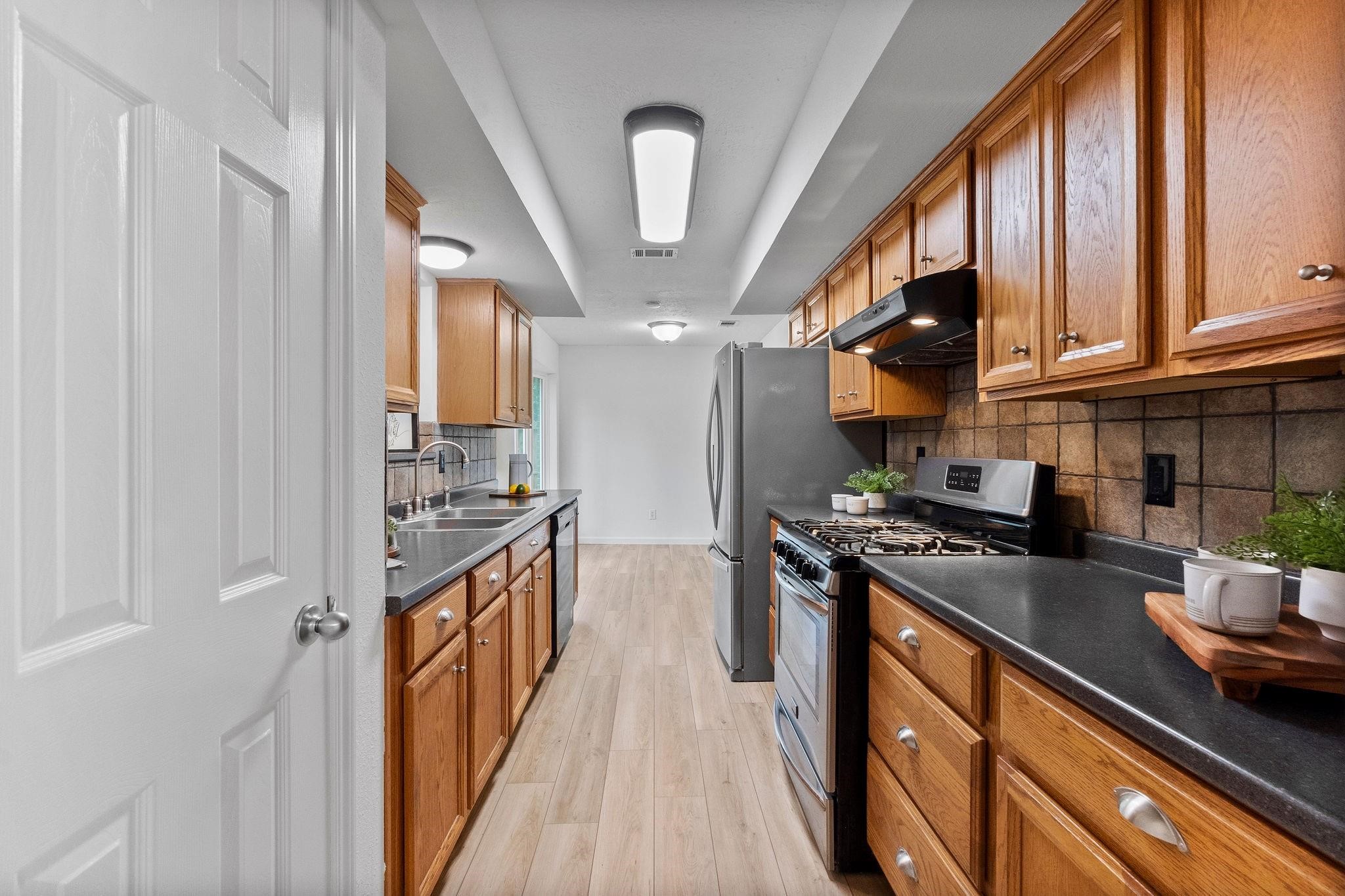 21710 Glenbranch Drive Spring, TX 77388 - Photo 10 of 32 a kitchen with stainless steel appliances granite countertop a sink a stove and a wooden floors