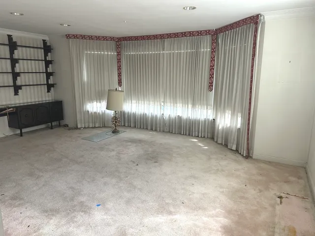 an empty room with windows and fireplace