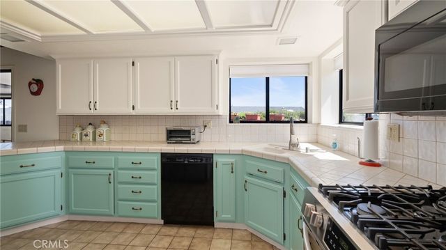 a kitchen with stainless steel appliances granite countertop a refrigerator and a view of living room