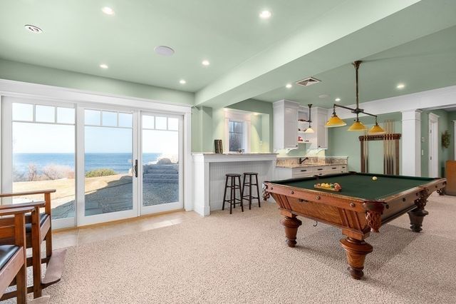 a room with wooden floor pool table and chairs