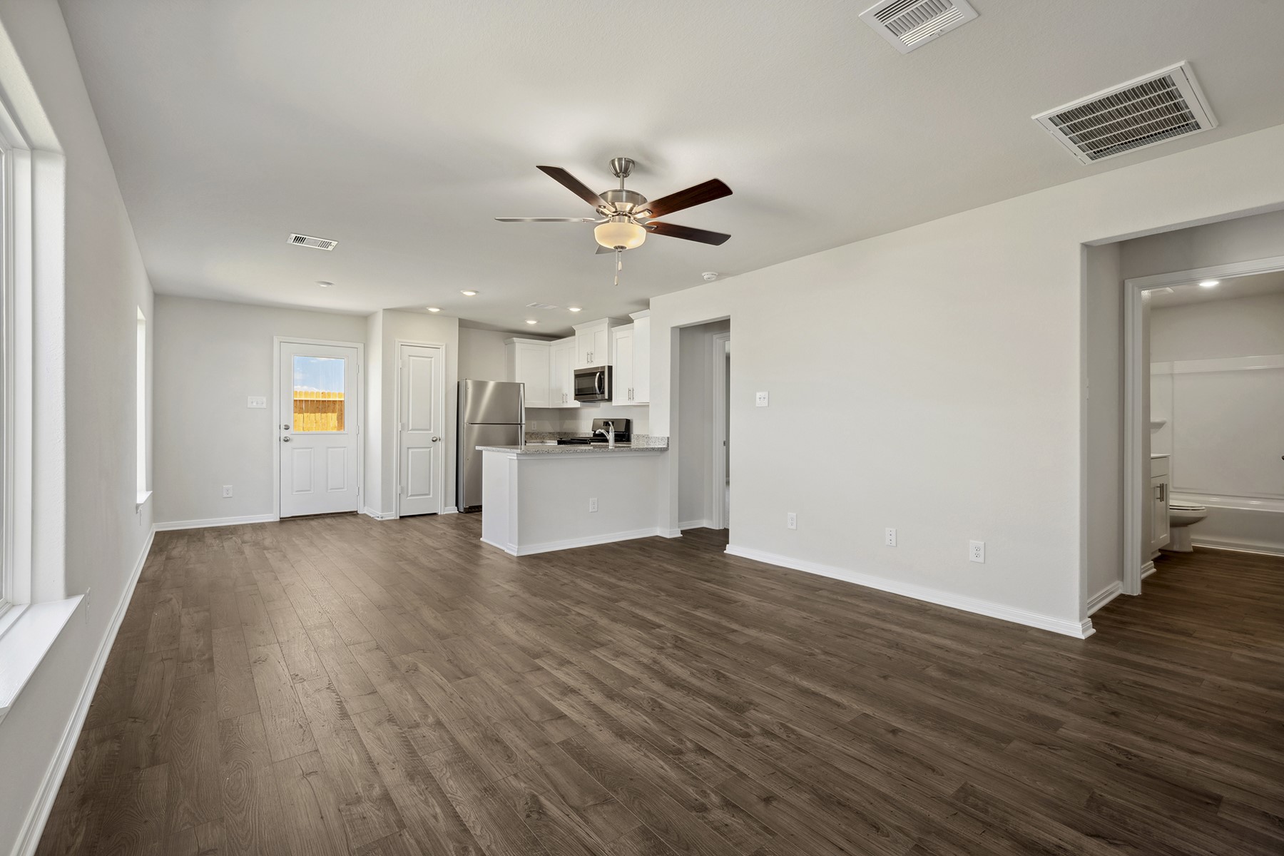 10430 Red Cardinal Drive Cleveland, TX 77328 - Photo 5 of 23 a view of a kitchen with a sink a ceiling fan and wooden floor